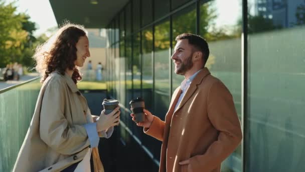 Két irodai dolgozó kávéval a kezében beszélget a szabadban. — Stock videók