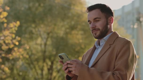 Uomo d'affari utilizzando smartphone moderno mentre in piedi sulla strada — Video Stock
