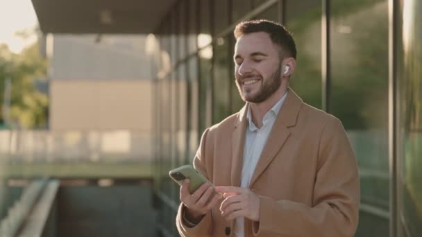 Homem elegante usando fones de ouvido e celular para ouvir música — Vídeo de Stock