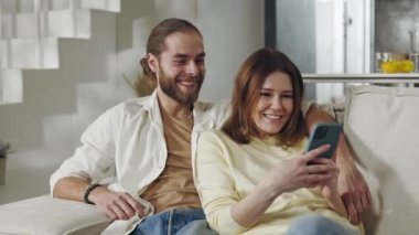 Mutlu çift koltukta dinlenirken akıllı telefon kullanıyor.