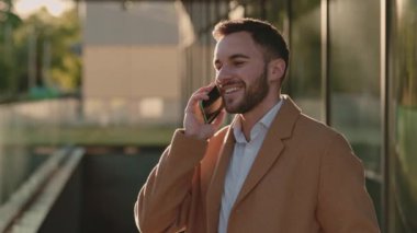 Ofis merkezine yakın duran ve cep telefonuyla konuşan bir adam.