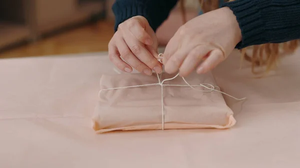 Depoda duran Kafkasyalı genç kadının yakın görüntüsü ve ahşap masadaki küçük pakete ip bağla. Küçük işletme kavramı.