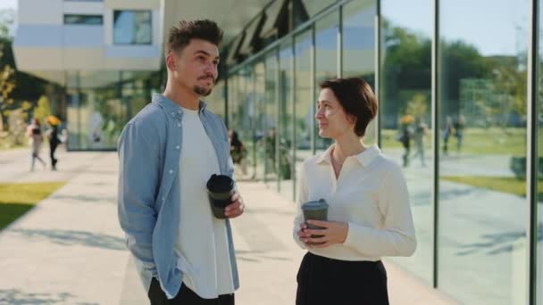 Чоловік і жінка розмовляють і п'ють каву біля офісного центру — стокове відео
