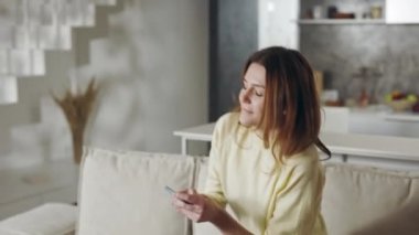 Kanepede otururken akıllı telefon kullanan güzel kadın.