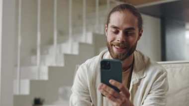 Mutlu adam koltukta oturuyor ve cep telefonuna mesajlar yazıyor.