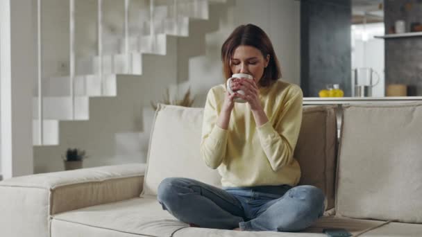 Kvinna dricker varmt te medan du vilar på soffan — Stockvideo