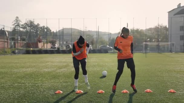 Two diverse women practicing on soccer field with cones — Stock Video