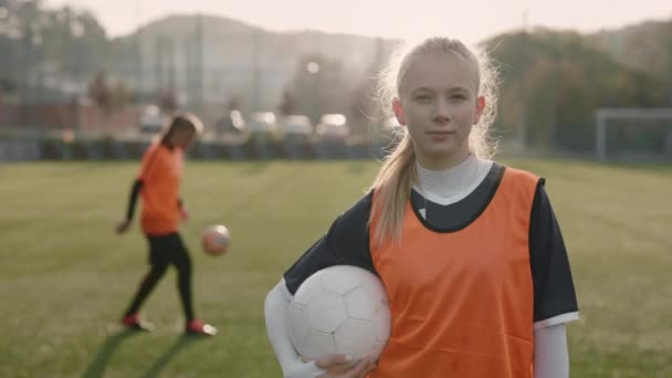 Female soccer player holding ball and looking at camera — Stock Video