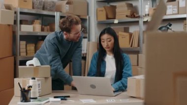 Asyalı meslektaşı klavyeye bir şey yazarken beyaz bir adam zevkle dizüstü bilgisayarına bakıyor. İnsanların keyfi yerinde. Küçük işletme kavramı.