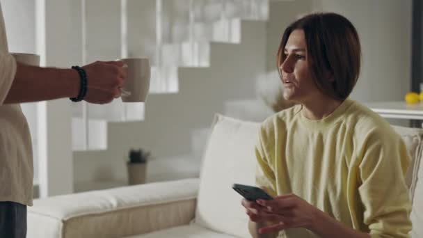 Kvinna som använder mobil på soffan medan man tar med sig te — Stockvideo