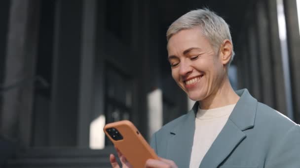 Smilende business lady tekstmeldinger på mobil utendørs – stockvideo