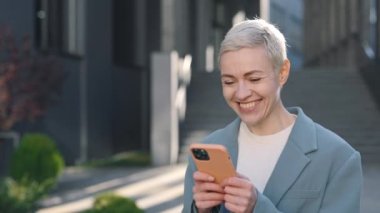 İş kadını cep telefonunda mesajlaşırken samimiyetle gülümsüyor