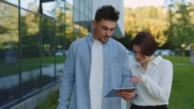 Dışarıda dururken tablet kullanan iki ofis çalışanı.