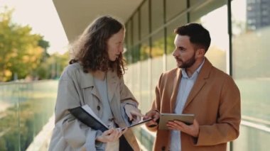 Tabletli ve panolu iş ortakları açık havada konuşuyor.