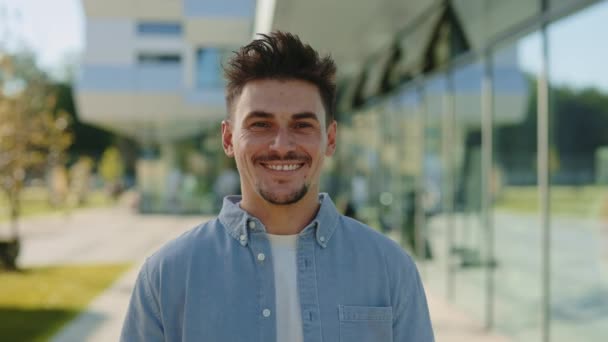 Young man smiling and looking at camera near office center — Stock Video