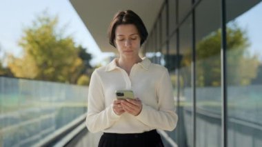 Beyaz kadın dışarıda dikilirken akıllı telefon kullanıyor.
