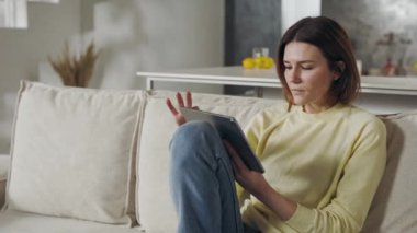 Evde boş zamanlarında tablet kullanan rahat bir kadın..