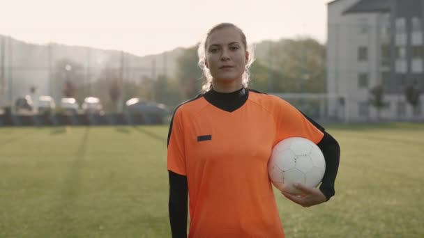 Female soccer player posing with ball on field — Stock Video
