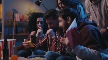 Happy friends rejoicing with real emotions and celebrating winning of favorite team while watching results of the game at the smartphone. Man holding flag and people looking at the screen in awaiting.