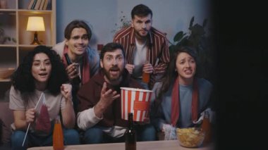 Excited diverse handsome euphoric football fans watching online games competition sports on TV and supporting favorite team while having fun entertainment at home. Sport and leisure concept.