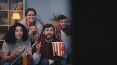 Excited diverse handsome euphoric football fans watching online games competition sports on TV and rejoicing victory while having fun entertainment at home. Sport and leisure concept.