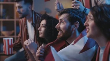 Memleketlerinde futbol maçı izleyen çeşitli çok ırklı arkadaşlar coşkuyla, tezahürat yaparak ve bir gol için sevinçle bekliyorlar. Evlerinde birbirini kucaklayan insanlar..