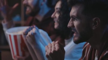 Genç taraftarlar TV 'de futbol maçı izliyor. Sakallı adam önce gergin, sonra mutlu. Favori takım gol atıyor, insanlar bağırıyor, gecenin karanlığında seviniyor. Futbol taraftarları konsepti.