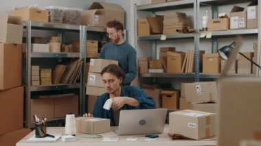 Esmer adam evinde oturuyor ve erkek arkadaşıyla dikkatlice çalışırken ciddi bir yüzle paketleri tarıyor. Posta servisi ve küçük işletme kavramı
