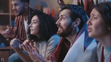 Futbol fanatiklerinin evdeki kanepede futbol maçı izleyen yaşam tarzı portresi. Favori takımı destekleyen gergin adamlar golü bekliyorlar. Eğlence konsepti