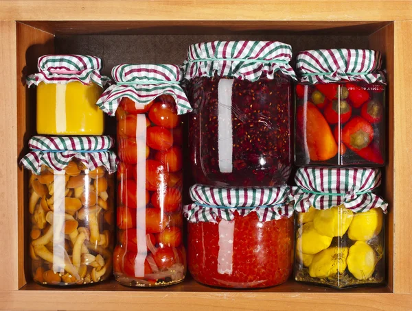 Many glass bottles stack with preserved food in wooden cabinet