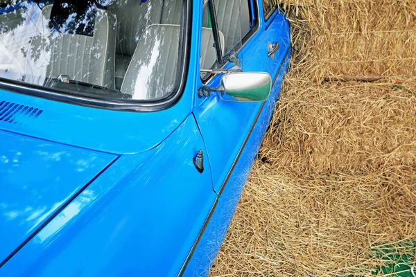 Part blue vintage car with a pile of straw. — Stock Photo, Image