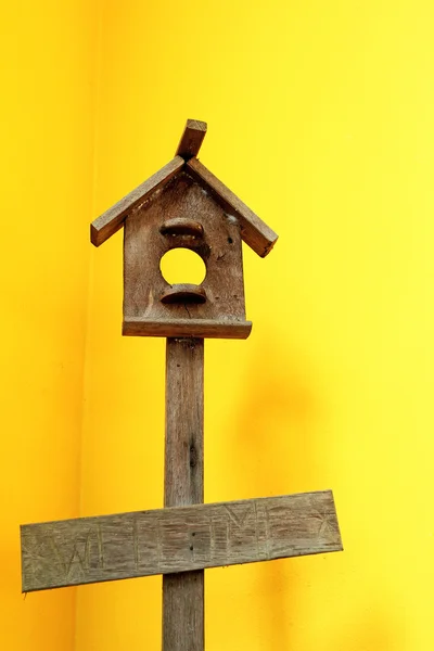 Casa de pássaro de madeira com parede amarela — Fotografia de Stock