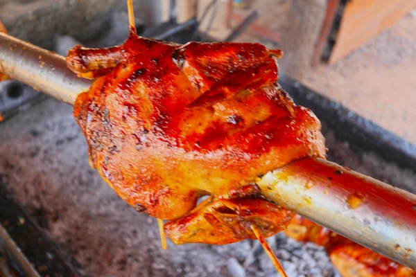 Whole grilled chicken on a grill with rotating steel plug. — Stock Photo, Image
