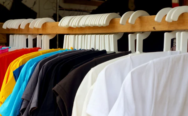 Shirts aus buntem Stoff hängen an einem Regal. — Stockfoto