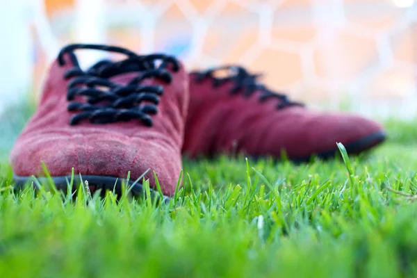 Röda skor grönt gräs i ett stadium. — Stockfoto