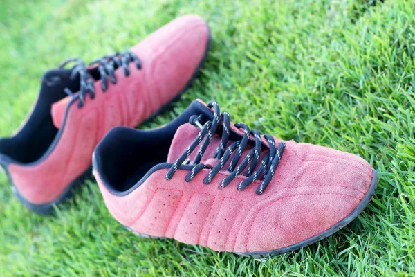 Rode schoenen groen gras in een stadion. — Stockfoto