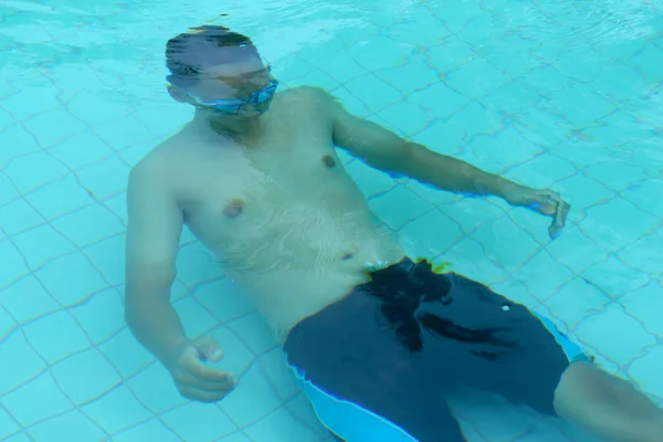Jonge jongen zwemmen in het zwembad. — Stockfoto
