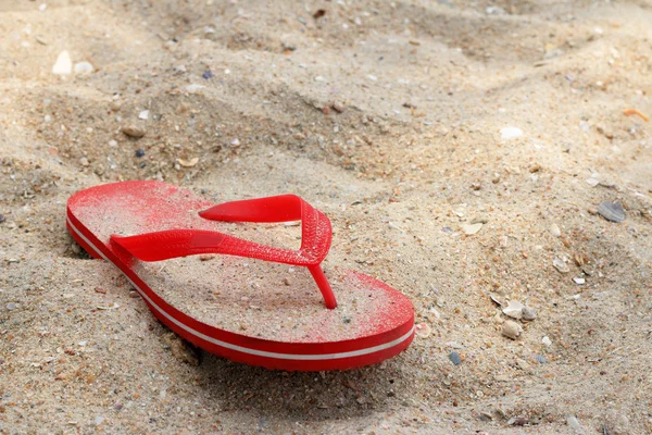 Красные резиновые шлепанцы на песке — стоковое фото