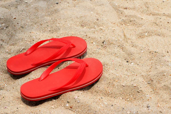 Red rubber flip-flops on the sand Stock Photo
