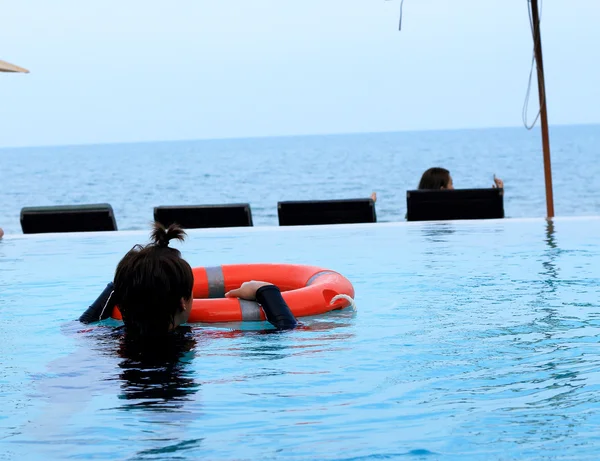 Mädchen schwimmt im Pool mit Rettungsring — Stockfoto