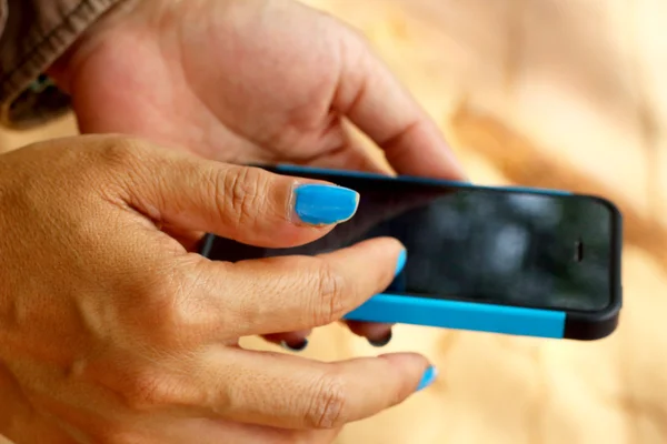妇女蓝色指甲油用手机. — 图库照片