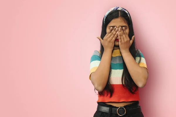 Young Indian Asian scared girl posing isolated covering eyes with hands. Confused girl close eyes with palms ignoring something. See no evil concept. Mock up copy space.