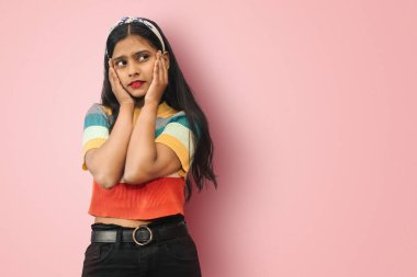 Genç Hintli Asyalı hayalperest neşeli bir kız avuçlarında avuçlar, sağ üst köşeye bakarken yalnız poz veriyor. Güzellik, moda ve yaşam tarzı konsepti. Kopyalama alanı oluştur.