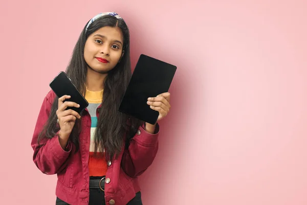 Genç Hintli Asyalı güler yüzlü tatlı kız izole edilmiş şekilde poz veriyor cep telefonu ve tablet kopyaları ile.