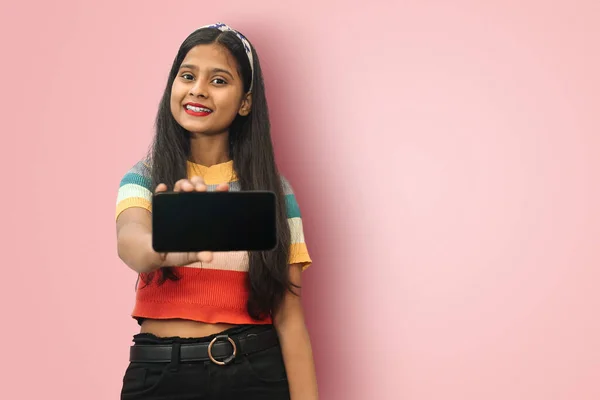 Genç Hintli Asyalı güler yüzlü tatlı kız izole edilmiş poz veriyor dokunmatik ekranlı cep telefonunu mesaj için boş yere bırakıyor..