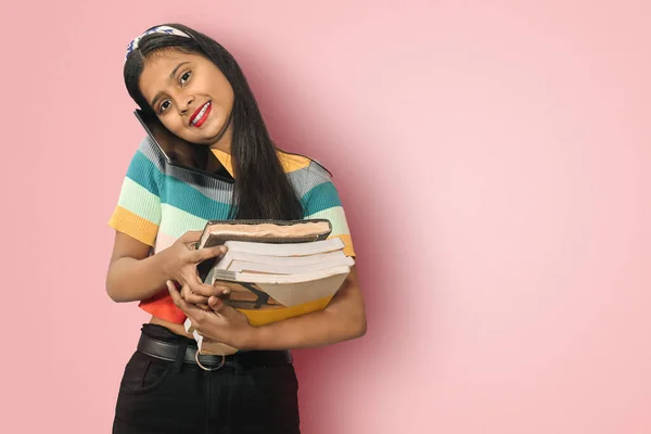 Sırıtkan Hintli Asyalı kız öğrenci elinde not defterleri tutarak ya da tablet üzerinde konuşarak ya da kopya alanının başarıya ulaşmasını sağlayacak ilginç bir fikri hayal ederek poz veriyor.