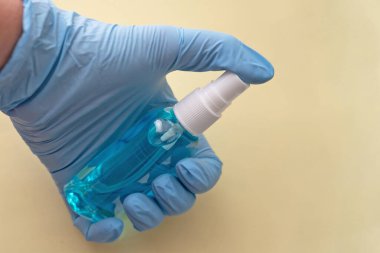 İnsan eliyle dezenfektan şişesi mavi elastik eldivenler, enfeksiyon önleyici hijyen ve sağlık koruma konsepti antibakteriyel ajan