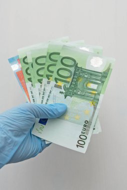 EURO banknotes in human hand in elastic blue medical glove