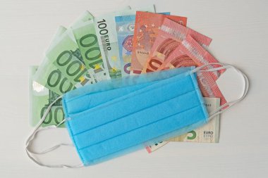 Medical facial masks on EURO banknotes money, deficit concept