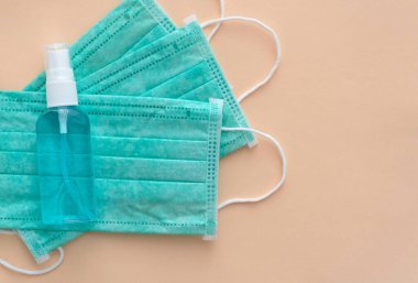 Medical masks and hand sanitizer blue bottle on pink background, anti-infective hygienic and health protection concept, Coronavirus Covid-19 protection 